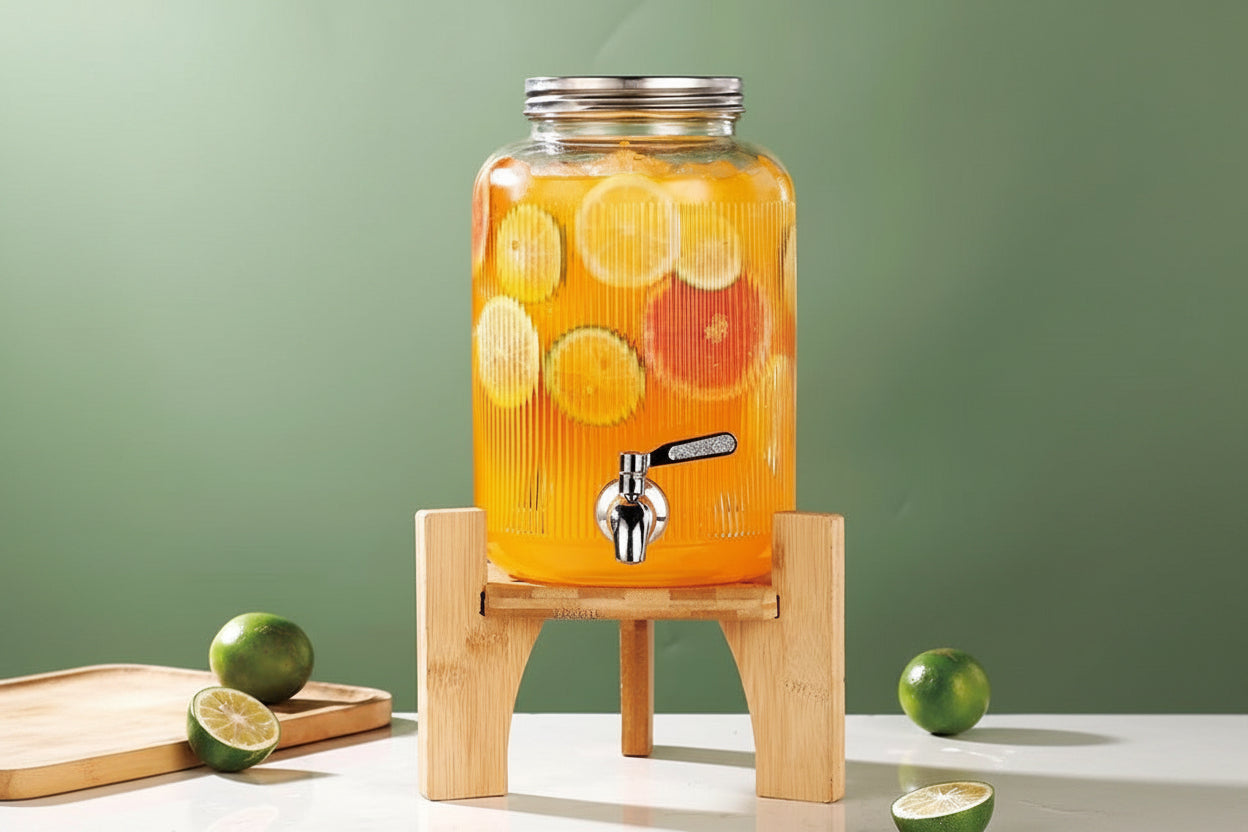 Juice dispenser with fruits on a wooden stand against a green background